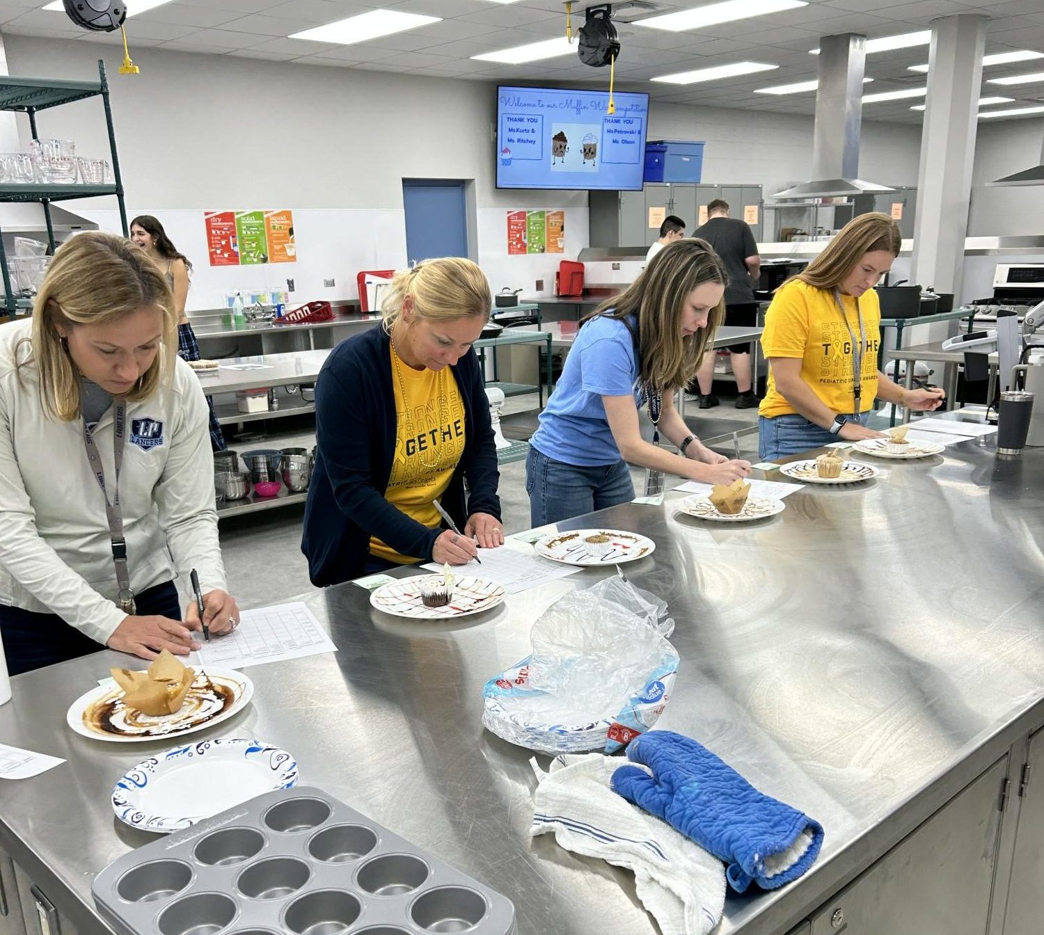 Faculty members judge a muffin baking contests taking place in Culinary Arts, making use of the new facilities.