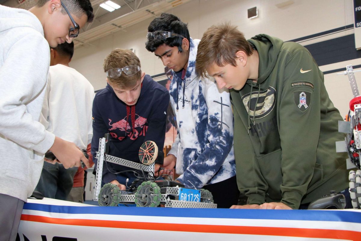 A team competing at Lake Park WC in a VEX Robotics competition inspects their robot last spring.